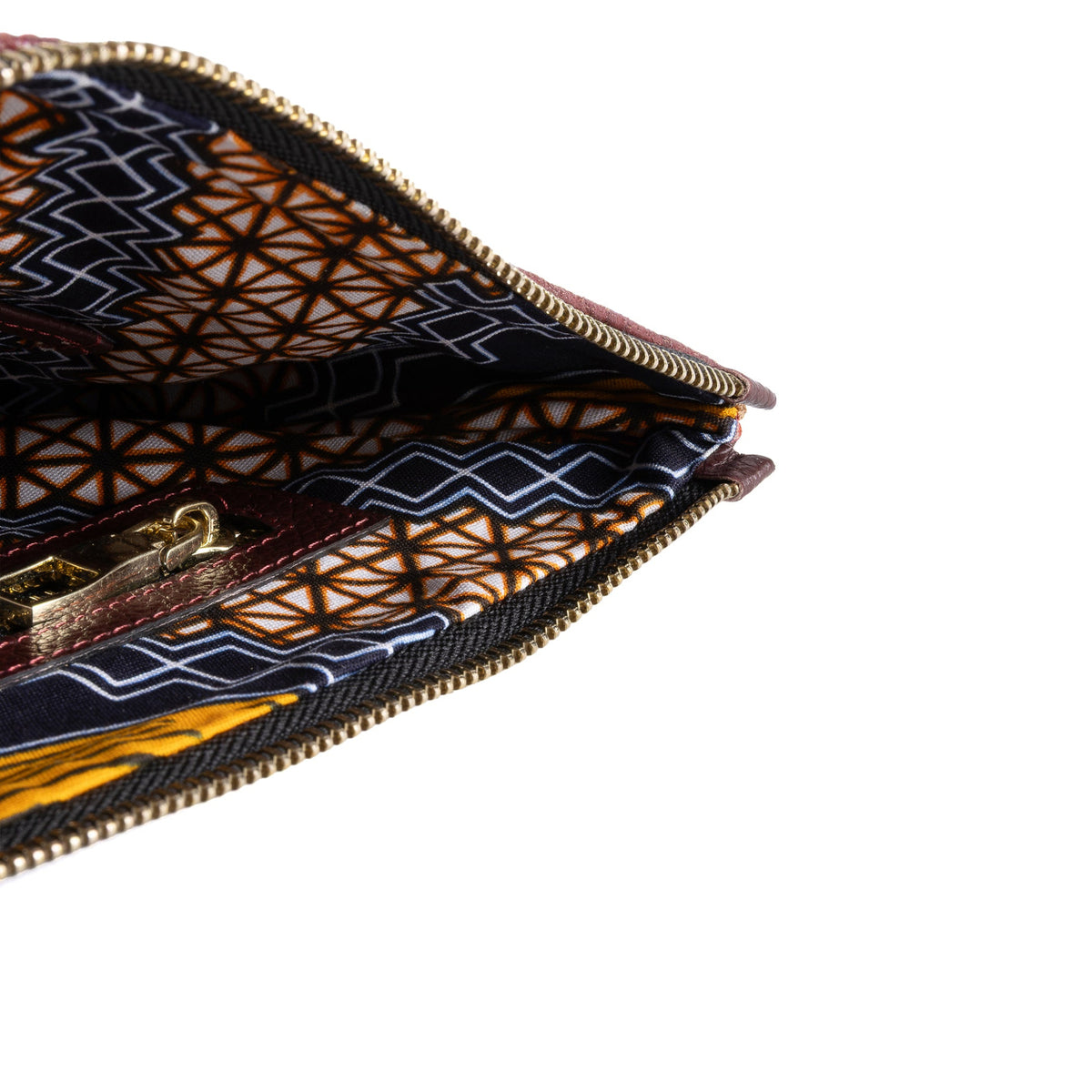 Close-up of a zippered clutch or wallet showing a dark navy and brown geometric patterned fabric lining with gold-toned zipper hardware, set against a plain white background.