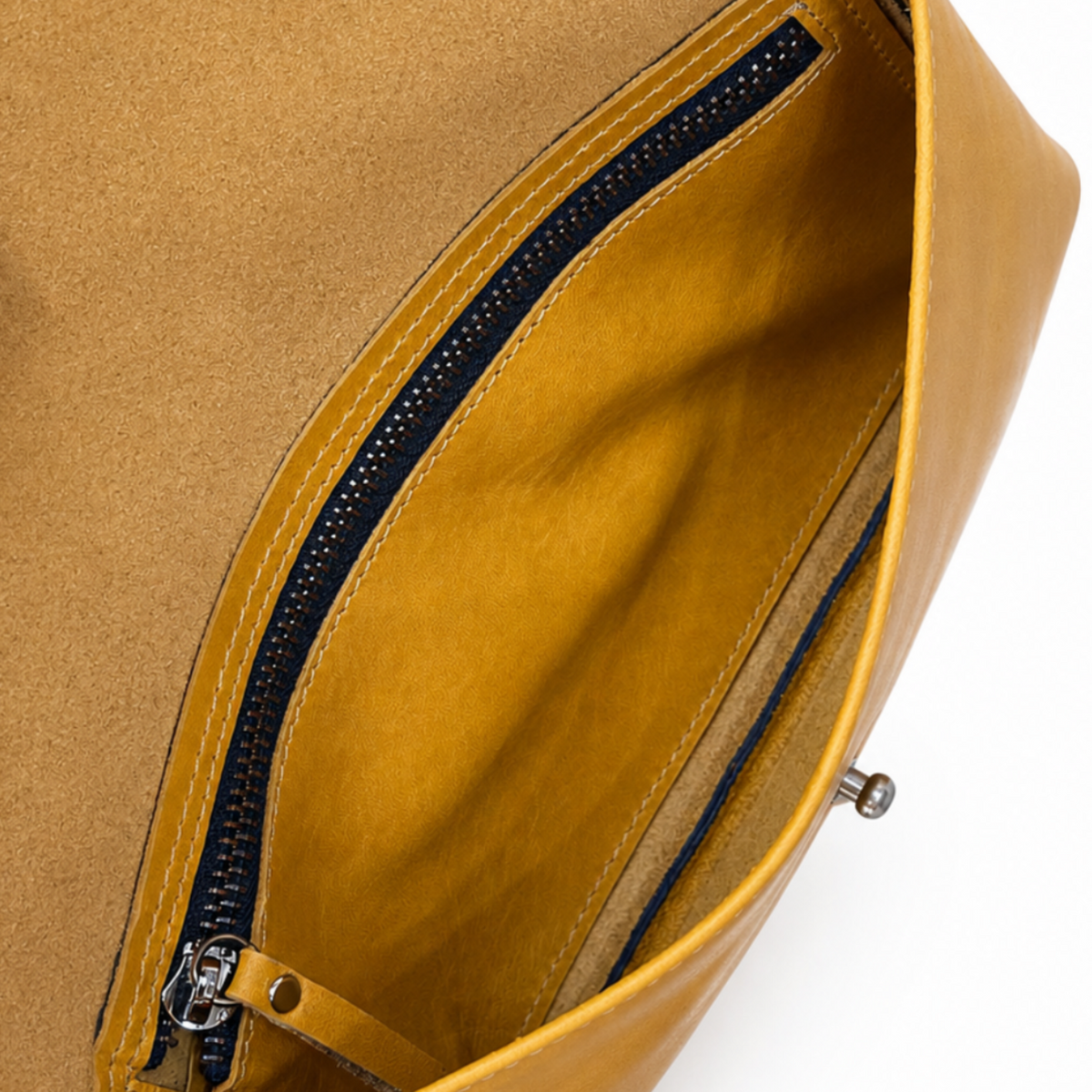 Close-up of a mustard yellow leather clutch or envelope-style bag opened to show a zippered interior pocket, with a finger holding one side against a white background.