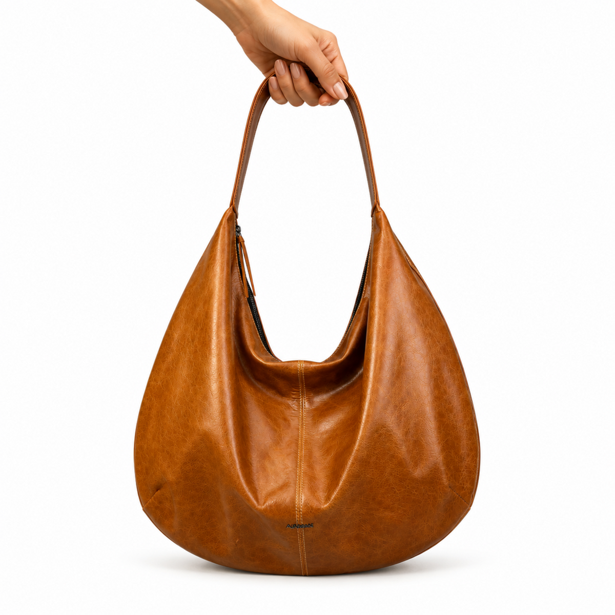 A brown leather hobo shoulder bag with a slouchy drape, held by a hand against a plain white background.